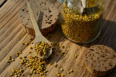 Kavanozda arı poleni ve tahta masada tahta kaşık. Apioterapi. Arı ürünleri