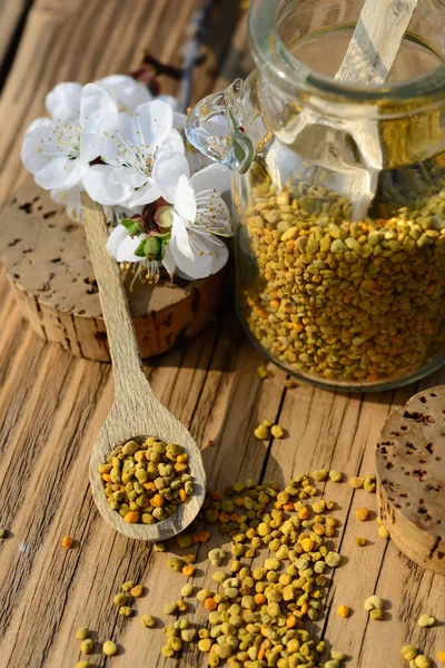 木製のテーブルの上に瓶や木製のスプーンで蜂の花粉の穀物 蜂製品だ 治療について — ストック写真