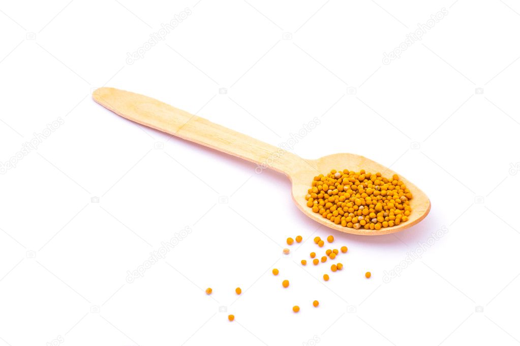 Mustard seeds in wooden spoon isolated on white