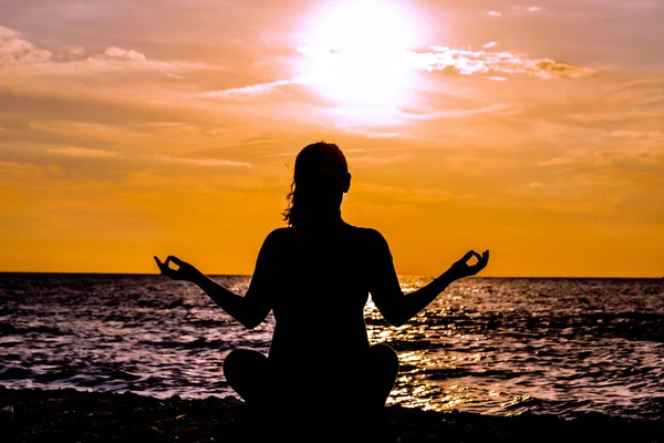 Female yoga lotos silhouette on beautiful beach during sunset. — Stock Photo, Image