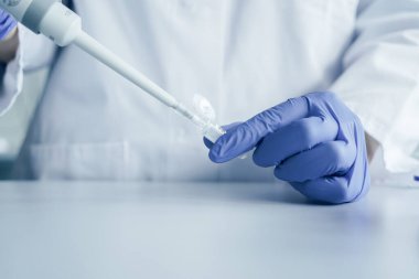 Pipet ve test tüpüyle çalışan bir bilim adamının elleri. Genetik laboratuarında araştırma teknisyeni.