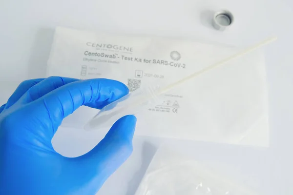 Rostock, Alemania - 10 de abril de 2019: Coronavirus test kit for COVID-19. mano en guante protector sostiene un tubo de ensayo con el hisopo de mucosidad — Foto de Stock
