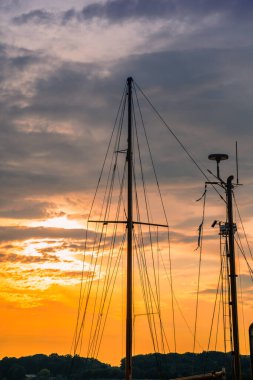Almanya 'da yelkenli teknelerle denizin üstünde renkli bir gün batımı, Rostock. Su yüzeyine yansıyan güneş. Deniz manzarası, yaz ve tatil konsepti
