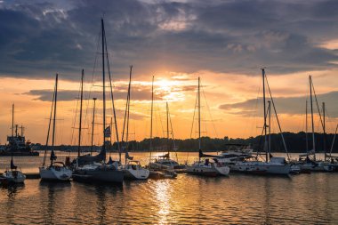 Almanya 'da yelkenli teknelerle denizin üstünde renkli bir gün batımı, Rostock. Su yüzeyine yansıyan güneş. Deniz manzarası, yaz ve tatil konsepti