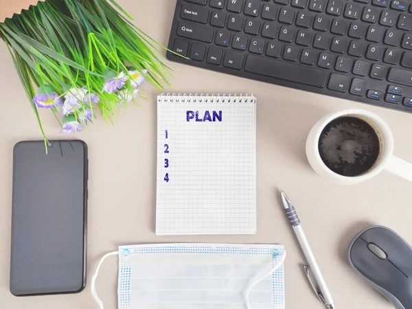 Plan list on the desk with notebook about the listing of goals and resolutions for the new year in coronavirus pandemic time. Flat lay to do list with copy space for the text and protective face mask