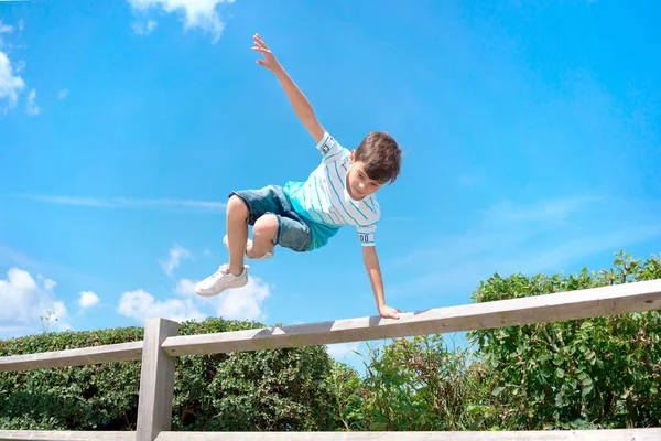 Chico saltando sobre la valla. Deportes y actividades para jóvenes. Infancia y ocio. Libertad y gente feliz. Imagen De Stock