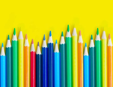 Sarı arka planda, kopya alanı olan kalemler. Okul ve renkli kalemlerle yaratıcı boya konsepti. Okula dönüş afişi