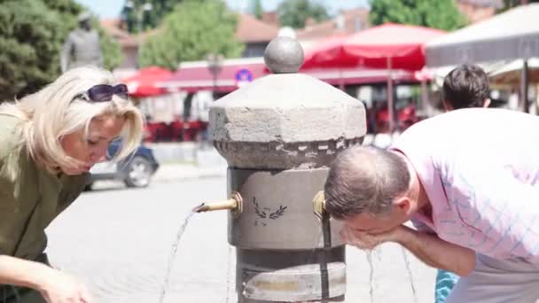 PRIZREN - KOSOVO, LUGLIO 2015: Persone che bevono acqua dal rubinetto orientale nella piazza del centro città . — Video Stock