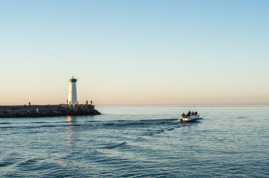 Fishermen at dawn with the lighthouse clipart