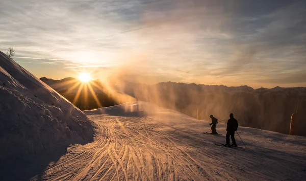 Sciatori sulla pista al tramonto — Foto Stock