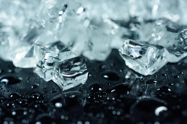 Trozos de hielo picado sobre fondo negro con gotas de agua — Foto de Stock