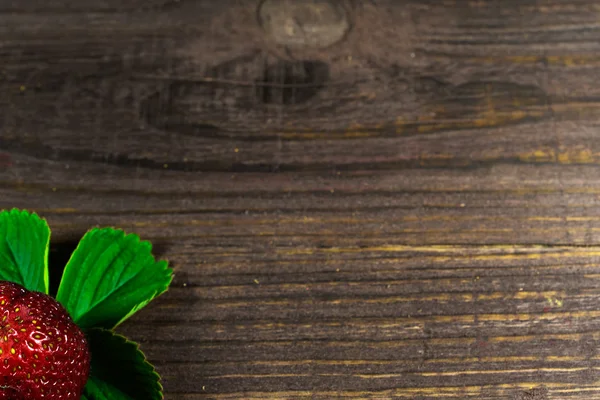 Satu stroberi matang segar dengan daun hijau di backgrou kayu tua — Stok Foto