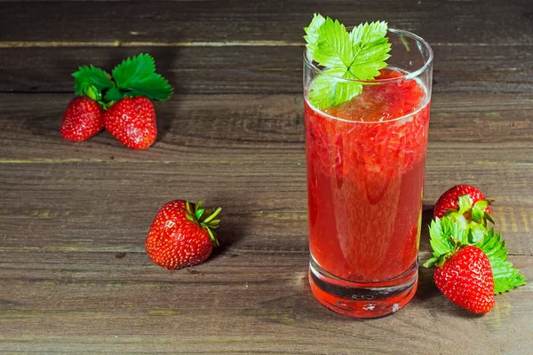 Fresas y jugo con pulpa en el vaso con hoja verde sobre fondo de madera —  Fotos de Stock