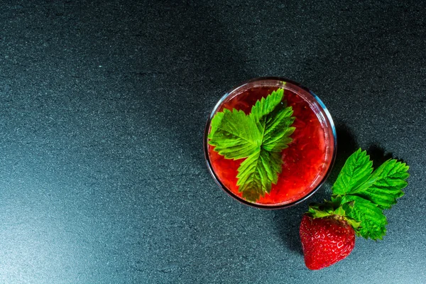 Fresa fresca y jugo con pulpa en un vaso con hoja verde —  Fotos de Stock