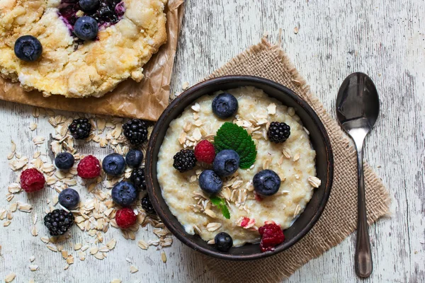 Healthy homemade oatmeal with berries and berry cake for breakfast. top view — Stock Photo, Image