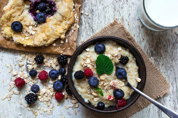 Healthy breakfast. homemade oatmeal with berries, blueberry cake and glass of milk. top view — Stock Photo, Image