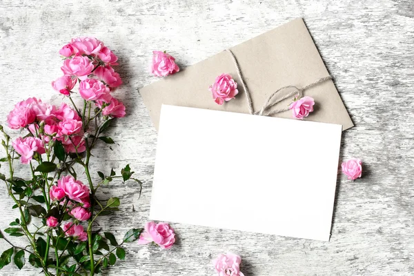 Ramo de rosas con una tarjeta de felicitación en blanco y sobre — Foto de Stock