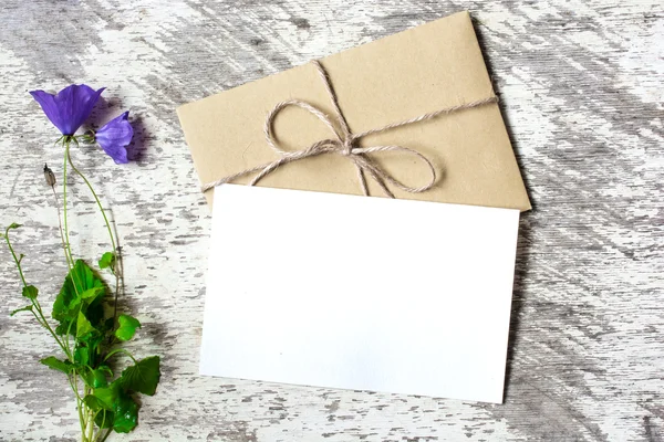 Tarjeta de felicitación blanca en blanco y sobre con flores silvestres azules con espacio de copia — Foto de Stock