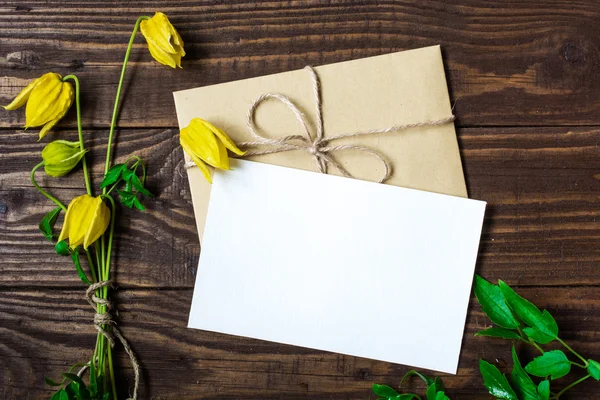 Boş beyaz tebrik kartı ve zarf ile sarı çiçekler — Stok fotoğraf