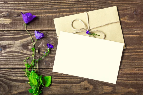 Buquê de flores silvestres roxas com cartão branco em branco e envelope — Fotografia de Stock