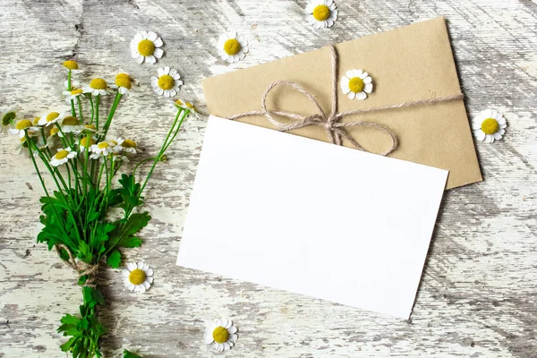 Tarjeta de felicitación en blanco y sobre con flores de manzanilla blanca — Foto de Stock