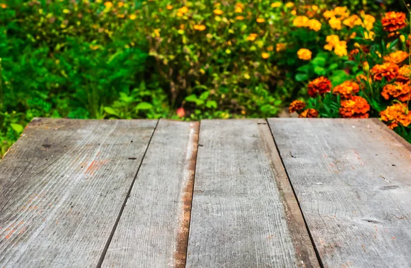Niewyraźne ogród jesień z kwiatów tła i biurko z drewna — Zdjęcie stockowe