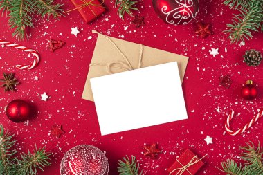 Noel tebrik kartı çerçevesinde hediyeler, köknar ağacı, şeker, kırmızı arka planda süslemeler. Model yap. Noel, kış, yeni yıl konsepti. Düz konum, kopyalama alanı olan üst görünüm