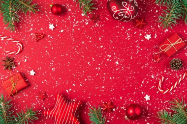 Noel kompozisyonu. Hediyelerden yapılmış çerçeve, köknar ağacı, şeker, kırmızı arka planda süslemeler. Noel, kış, yeni yıl konsepti. Düz konum, kopyalama alanı olan üst görünüm