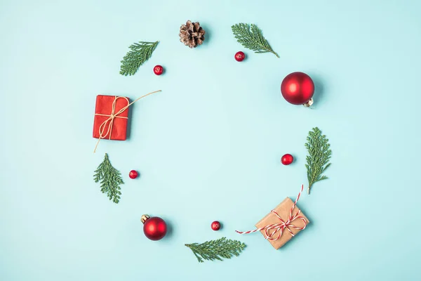 Christmas or Happy New Year card made of fir tree branches, holiday decorations and gift boxes on blue background. flat lay. top view with copy space