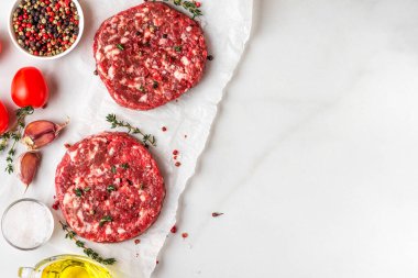 Beyaz arka planda pişirmek için çiğ sığır eti köftesi ya da baharatlı pirzola. Kopyalama alanı olan üst görünüm