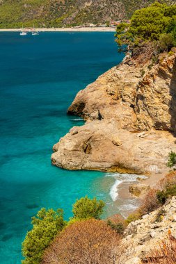 Türkiye 'nin Mugla bölgesinde Oludeniz ilçesi yakınlarında turkuaz suyu bulunan güzel bir sahil. Dikey oryantasyon. Seyahat hedefi
