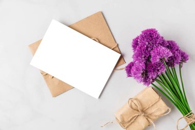 Boş tebrik kartı ve beyaz arka planda hediye kutusu olan mor alium çiçekleri. Üst Manzara. Model yap. Düz yat. düğün ya da tatil konsepti. şenlikli arkaplan