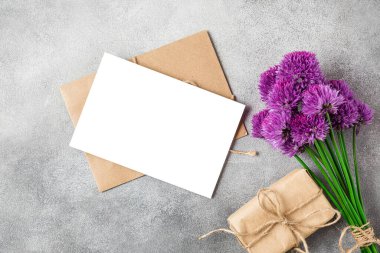 Mor kır çiçekleri buketi ve çimento kaplı hediye kutusu olan boş bir tebrik kartı. Üst Manzara. Model yap. Düz yat. düğün ya da tatil konsepti. şenlikli arkaplan