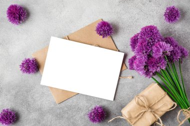Boş tebrik kartı ve çimento arka planda hediye kutusuyla mor alium çiçekleri. Üst Manzara. Model yap. Düz yat. düğün ya da tatil konsepti. şenlikli arkaplan