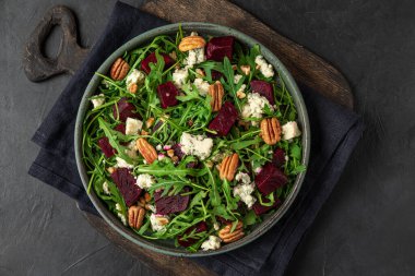 Siyah arka planda taze roka, mavi peynir ve fındıklı pancar salatası. Üst Manzara. sağlıklı vejetaryen yemekleri
