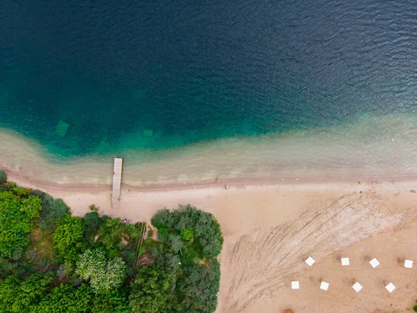 Aerial view of the coast of the lake with the pier, sandy beach and forest . top view. shot from drone. Landscape photography