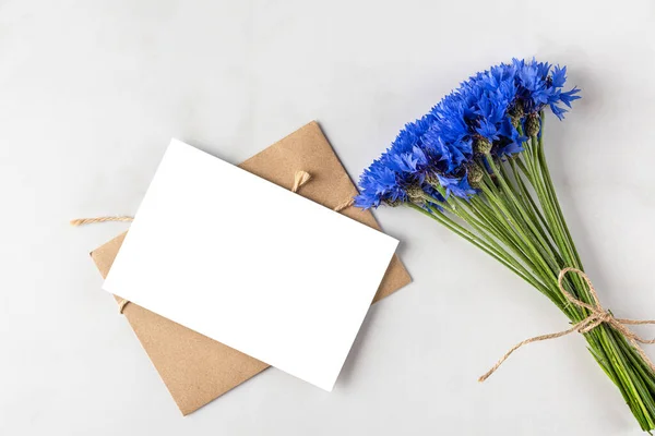 白色大理石背景的蓝色玉米花花束的空白贺卡 顶视图 平躺在床上模仿 节假日概念 — 图库照片