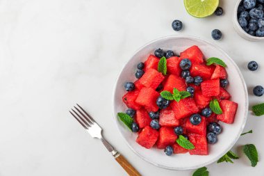 Beyaz arka planda taze yaz karpuzu ve nane ve limon suyu ile yaban mersini salatası. Kopyalama alanı olan üst görünüm. Sağlıklı yemek.
