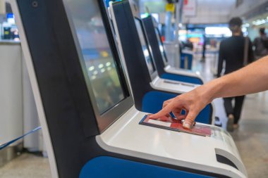 Close up of traveler scanning passport at self service check-in kiosk in modern airport terminal. Automated machine for ease and efficiency of air travel. Technology, automation and digital identity