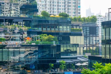 Modern glass building with rooftop gardens, layered terraces and green plants in central Bangkok city, Thailand. Green architecture, biophilic design, environmental responsibility and sustainable