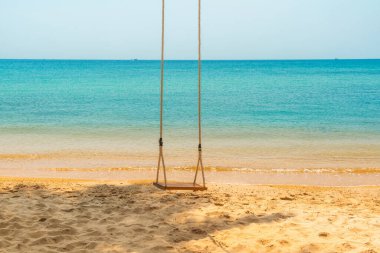 Vietnam 'daki Phu Quoc adasında tropikal sahilde altın kum ve sakin turkuaz deniz salıncağında asılı duran tahta salıncak. Tatil, minimalizm, sakinlik, rahatlama, tropikal kaçış ve Asya 'da seyahat.