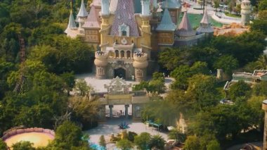 Aerial view of fairy tale castle and amusement park surrounded by lush greenery in Central of Vinwonders theme park Vinpearl on Phu Quoc island, Vietnam. Entertainment promotion, family adventure.