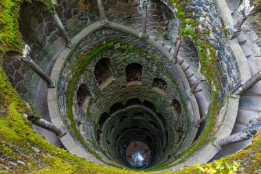 Portekiz 'in Sintra şehrindeki Quinta da Regaleira' daki Kabul Kuyusu 'nun içindeki spiral taş merdiven. Lisbon City yakınlarındaki bir parkta gotik mimari. Seyahat ve turistik dönüm noktası. Simetri, spiral biçimler
