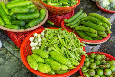 Assortment of fresh green vegetables displayed at traditional food market in Phu Quoc, Vietnam. Okra, bitter melon, white eggplant, cucumbers and long gourds displayed at Vietnamese street market