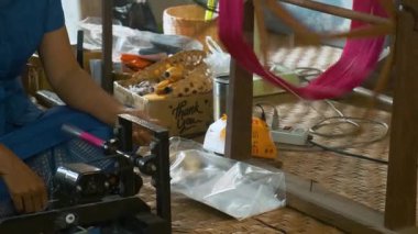 İpek fabrikasında ipek çevirme işlemi, Chiang Mai, Tayland. Kadın geleneksel ahşap makara üzerinde kırmızı ipek iplikler ördü. Tekstil üretimi zanaatkarlığı, serikültür süreci