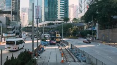 Hong Kong, Çin - 16 Aralık 2025: Çift katlı tramvaydan hareketli Hong Kong caddesinde, modern yüksek binalar arasında geçen tramvaylar, otobüsler ve arabalar.