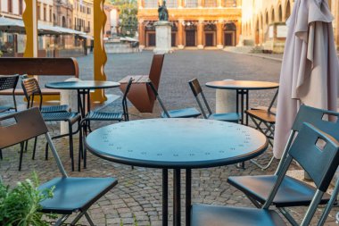 İtalya 'nın Rimini kentinde bulunan Piazza Cavour' daki kaldırım taşlarının üzerinde heykeller ve sandalyeler bulunuyor. Gündoğumunda kimse olmayan İtalyan sokak restoranı..