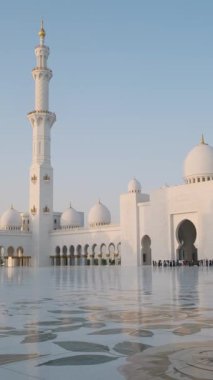 Büyük avlu ve Şeyh Zayed Büyük Camii 'nin girişi beyaz kubbeler, minare ve mermer zemindeki yansımaları Birleşik Arap Emirlikleri Abu Dabi' de açık mavi gökyüzünün altında. Arap mimarisi. Seyahat