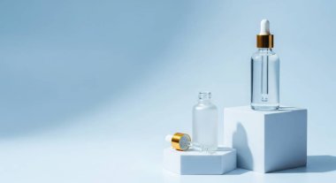 Beyaz podyumlarda mavi arka planda kozmetik serum şişeleri. Yüz bakımı için güzellik ürünü. Modern tarz ve zarif konsept..