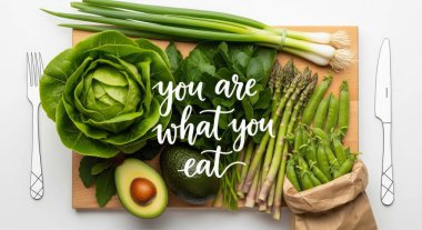 Healthy eating concept with fresh organic vegetables on wooden board. Spring onion, asparagus, peas, avocado, cabbage and spinach. Isolated on white background.